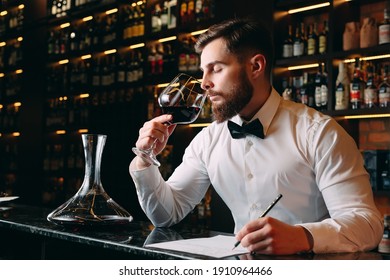 Young handsome man sommelier tasting red wine in cellar