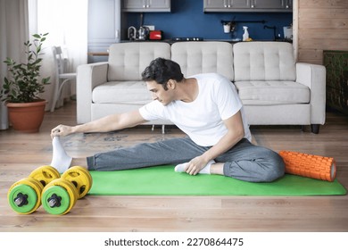 Young handsome man in sportswear do exercises at home. Healthy lifestyle and self isolation concept