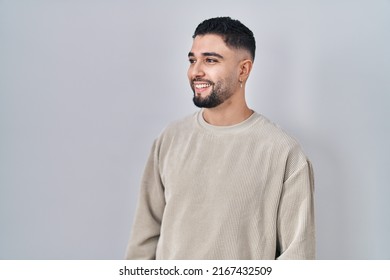 Young Handsome Man Standing Over Isolated Background Looking Away To Side With Smile On Face, Natural Expression. Laughing Confident. 