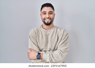 Young handsome man standing over isolated background happy face smiling with crossed arms looking at the camera. positive person.  - Powered by Shutterstock