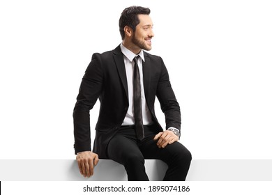 Young Handsome Man In A Suit Sitting On A Panel Isolated On White Background