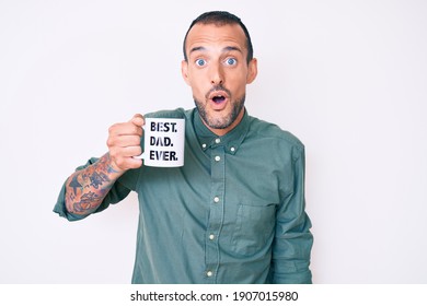 Young Handsome Man With Tattoo Drinking Mug Of Coffe With Best Dad Ever Message Scared And Amazed With Open Mouth For Surprise, Disbelief Face 