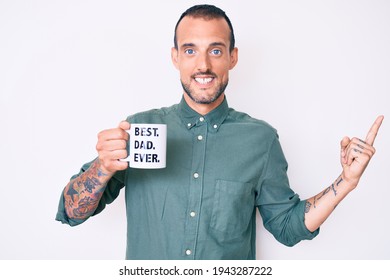 Young Handsome Man With Tattoo Drinking Mug Of Coffe With Best Dad Ever Message Smiling Happy Pointing With Hand And Finger To The Side 