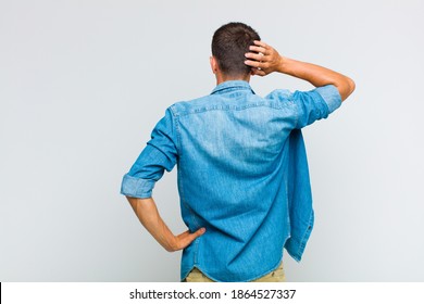 young handsome man thinking or doubting, scratching head, feeling puzzled and confused, back or rear view - Powered by Shutterstock