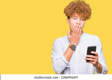 Young handsome man using smartphone cover mouth with hand shocked with shame for mistake, expression of fear, scared in silence, secret concept