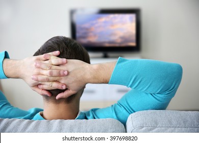 Young Handsome Man Watching TV On A Sofa At Home