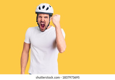 Young handsome man wearing bike helmet angry and mad raising fist frustrated and furious while shouting with anger. rage and aggressive concept.  - Shutterstock ID 1837973695