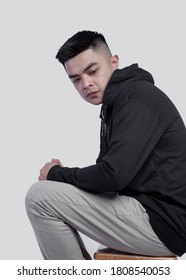 Young Handsome Man Wearing Black Zip Hoodie Is Sitting On A Chair Isolated On Background