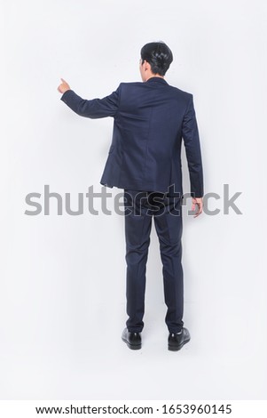 Young handsome man wearing black suit standing shirt over isolated white background Posing backwards pointing ahead with finger hand


