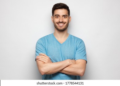 Young Handsome Man Wearing Blue Tshirt, Standing With Crossed Arms, Isolated On Gray Background