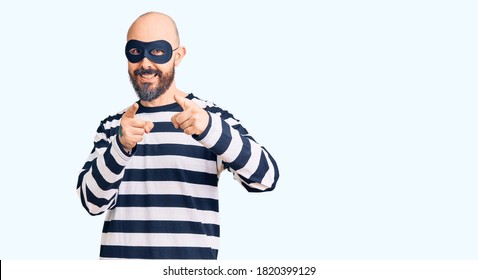 Young Handsome Man Wearing Burglar Mask Pointing Fingers To Camera With Happy And Funny Face. Good Energy And Vibes. 