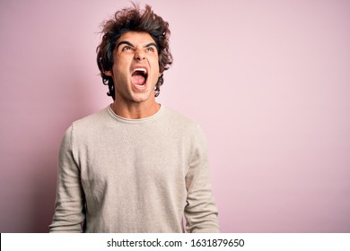 Young handsome man wearing casual t-shirt standing over isolated pink background angry and mad screaming frustrated and furious, shouting with anger. Rage and aggressive concept. - Shutterstock ID 1631879650