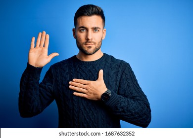 Young handsome man wearing casual sweater standing over isolated blue background Swearing with hand on chest and open palm, making a loyalty promise oath - Shutterstock ID 1687632352