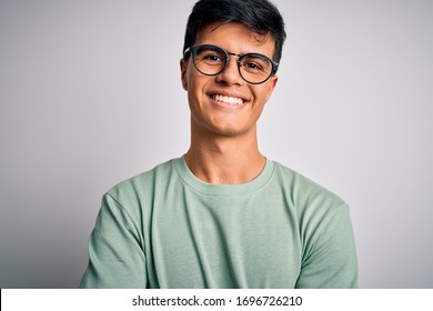 Young Handsome Man Wearing Casual T-shirt And Glasses Over Isolated White Background Happy Face Smiling With Crossed Arms Looking At The Camera. Positive Person.