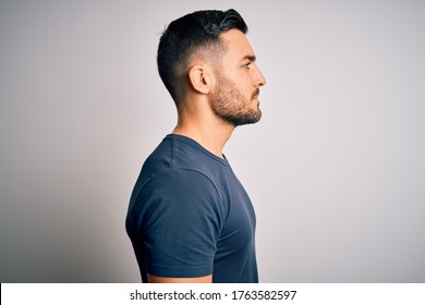 Young Handsome Man Wearing Casual T-shirt Standing Over Isolated White Background Looking To Side, Relax Profile Pose With Natural Face With Confident Smile.