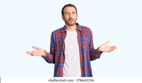 Young Handsome Man Wearing Casual Clothes Clueless And Confused With Open Arms, No Idea Concept. 