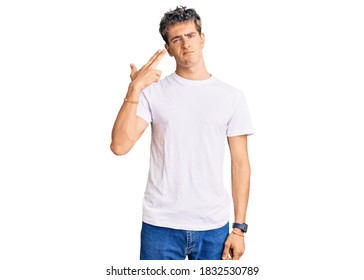 Young Handsome Man Wearing Casual White Tshirt Shooting And Killing Oneself Pointing Hand And Fingers To Head Like Gun, Suicide Gesture. 