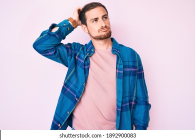 Young handsome man wearing casual clothes confuse and wondering about question. uncertain with doubt, thinking with hand on head. pensive concept. 