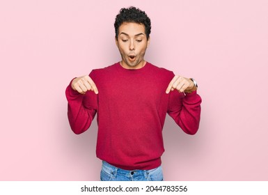 Young handsome man wearing casual clothes pointing down with fingers showing advertisement, surprised face and open mouth 