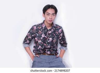 Young Handsome Man Wearing Casual Shirt With White Pants Sitting In Studio,

