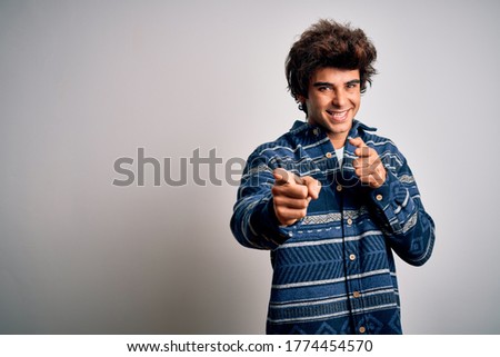 Young handsome man wearing casual shirt standing over isolated white background pointing fingers to camera with happy and funny face. Good energy and vibes.