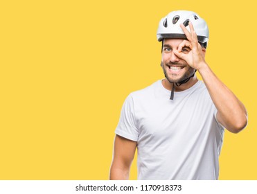 Young handsome man wearing cyclist safety helmet over isolated background doing ok gesture with hand smiling, eye looking through fingers with happy face.