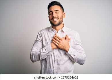 Young Handsome Man Wearing Elegant Shirt Standing Over Isolated White Background Smiling With Hands On Chest With Closed Eyes And Grateful Gesture On Face. Health Concept.