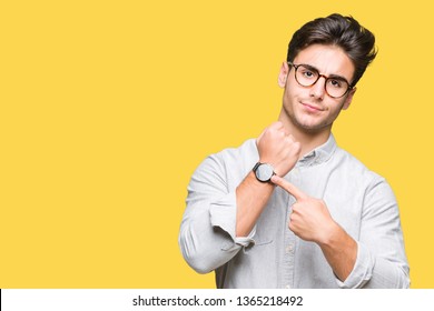 Young handsome man wearing glasses over isolated background In hurry pointing to watch time, impatience, upset and angry for deadline delay