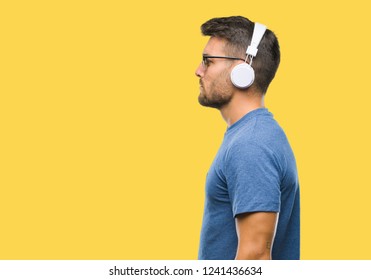 Young Handsome Man Wearing Headphones Listening To Music Over Isolated Background Looking To Side, Relax Profile Pose With Natural Face With Confident Smile.