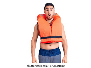 Young Handsome Man Wearing Lifejacket Scared And Amazed With Open Mouth For Surprise, Disbelief Face 