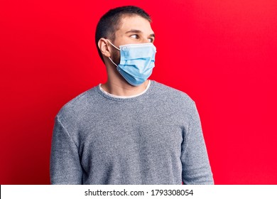 Young Handsome Man Wearing Medical Mask Looking To Side, Relax Profile Pose With Natural Face And Confident Smile. 