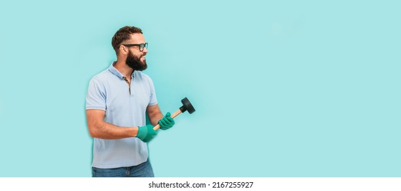 Young handsome man wearing plumber uniform holding toilet plunger looks happy. Professional cleaning of clogged pipes. Studio shot on blue background. Funny promotion poster