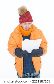 Young Handsome Man Wearing In Red Hat And Yellow Down Jacket Feeling Cold Hold High Electricity Gas Bill On White Background. Gas Crisis Concept