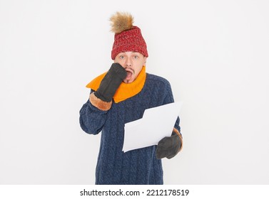 Young Handsome Man Wearing In Red Hat And Blue Pullover Feeling Cold Hold High Electricity Gas Bill On White Background. Gas Crisis Concept