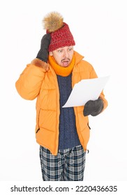 Young Handsome Man Wearing In Red Hat And Yellow Down Jacket Feeling Cold Hold High Electricity Gas Bill On White Background. Gas Crisis Concept