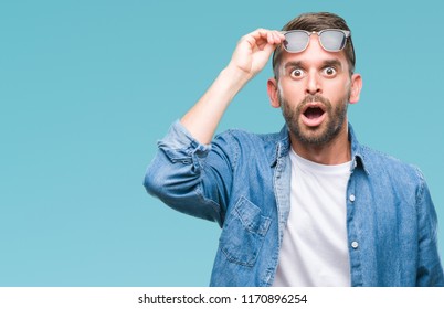 Young Handsome Man Wearing Sunglasses Over Isolated Background Afraid And Shocked With Surprise Expression, Fear And Excited Face.