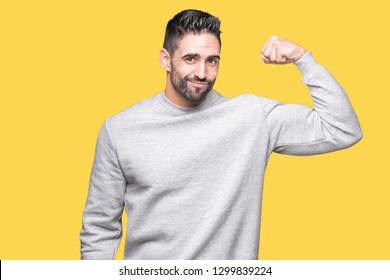 Young Handsome Man Wearing Sweatshirt Over Isolated Background Strong Person Showing Arm Muscle, Confident And Proud Of Power