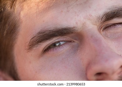 Young Handsome Man Winking Looking At The Camera . Close Up View Of Light Brown Eyes