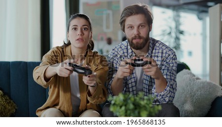 Young handsome man and woman in love spending fun leisure activity playing console videogames with joysticks. Concepot for excitement, competition, entertainment.