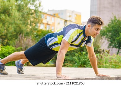 Young handsome man working out outdoor. Sporty guy flexing his muscles doing push ups.