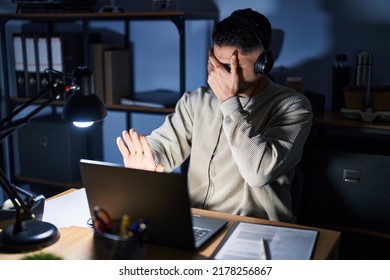 Young Handsome Man Working Using Computer Laptop At Night Covering Eyes With Hands And Doing Stop Gesture With Sad And Fear Expression. Embarrassed And Negative Concept. 