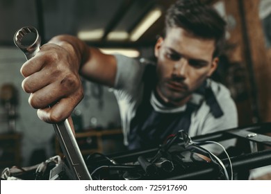 young handsome mechanic repairing motorbike in workshop - Powered by Shutterstock