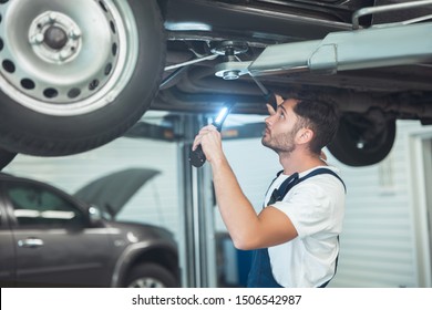 Young Handsome Mechanic Working In Car Service Department Scanning The Problem In Vehicle Chassis