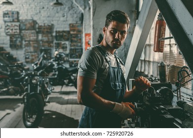 young handsome mechanic working in repair shop in motorcycle - Powered by Shutterstock