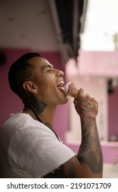 Young Handsome Mexican Tattooed Man Eating Ice Cream In A Waffle Cone.