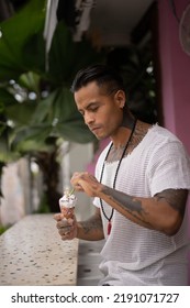 Young Handsome Mexican Tattooed Man Eating Ice Cream In A Waffle Cone.