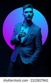 Young handsome model posing in a studio in a trendy neon light. Fashionable man in a stylish suit. Vibrant color. Bright colorful light effects. Disco style. Overlay. Gel filter. Supersaturated