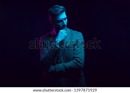 Young handsome model posing in a studio in a trendy neon light. Fashionable man in a stylish suit. Vibrant color. Bright colorful light effects. Disco style. Overlay. Gel filter. Supersaturated