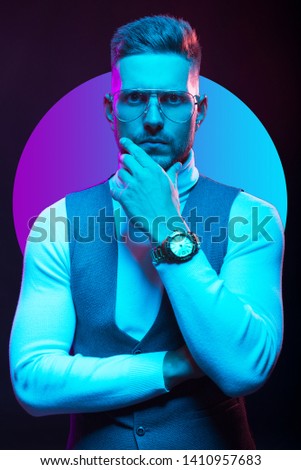Young handsome model posing in a studio in a trendy neon light. Fashionable man in a stylish suit. Vibrant color. Bright colorful light effects. Disco style. Overlay. Gel filter. Supersaturated