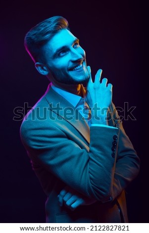 Young handsome model posing in a studio in a trendy neon light. Fashionable man in a stylish suit. Vibrant color. Bright colorful light effects. Disco style. Overlay. Gel filter. Supersaturated